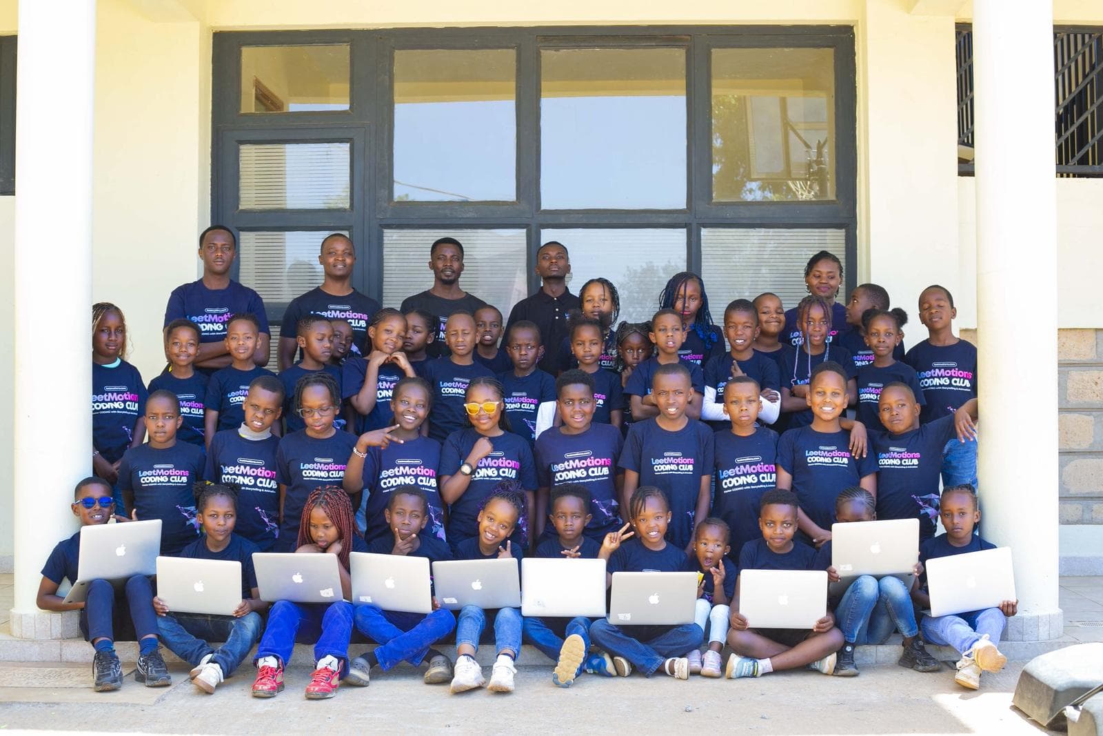 A LeetCamp cohort with their instructors, holding laptops