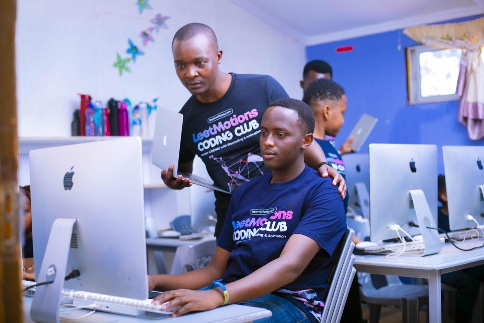 An instructor working alongside an older learner at an iMac